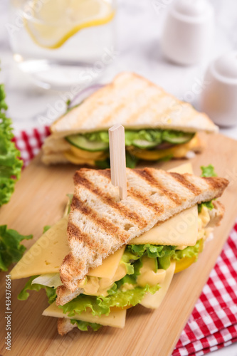 Wooden board with tasty cheese sandwich on table