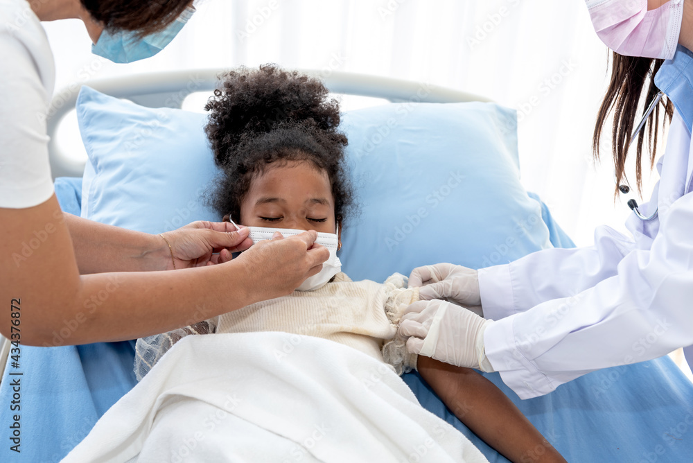 5 year old African girl wearing a surgical mask Lying in a patient's bed, being treatment by a team of doctor for flu virus infection, to African black skin and health care concept. 5 year old African girl wearing a surgical mask Lying in a patient's bed, being treatment by a team of doctor for flu virus infection, to African black skin and health care concept.