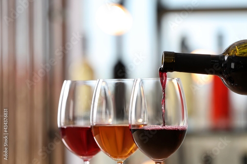Canvastavla Pouring red wine from bottle into glass indoors, closeup