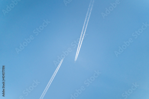 Two aircrafts approach each other in the clear, blue sky.
