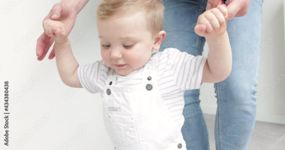 Baby boy happy about taking first steps with help from mum Baby boy happy about taking first steps with help from mum