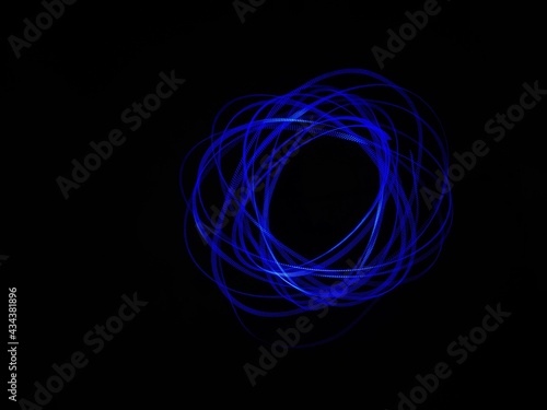Closeup of Neon blue Spirograph geometric pattern abstract isolated in a Black background. Made using light Painting technique, long exposure. Pendulum pattern. Light trails. Waves. Rays. Chakra.