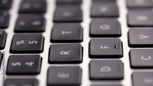 Macro shot of laptop keyboard. Camera movement along the keyboard, some keys are blurred. Slow motion. Close up. photo