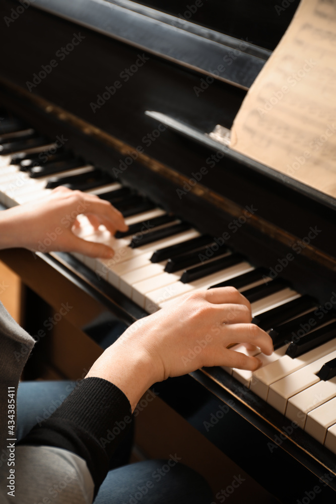 Fototapeta premium Young woman playing piano, closeup. Music lesson