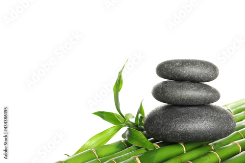Stack of spa stones on bamboo stems against white background
