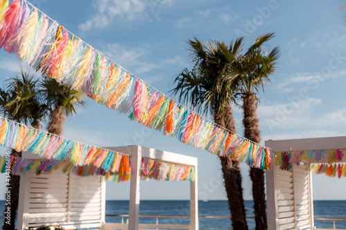 Multicolored garlands fringe with tassels on a summer beach playground.