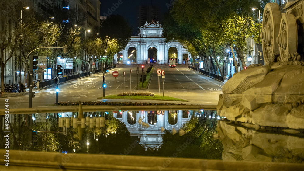 Estatua a la diosa Cibeles y vistas a la Puerta de Alcalá con el reflejo en el agua de la fuente, en una noche cálida con pocas nubes