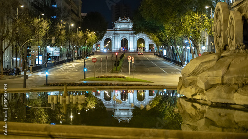 Estatua a la diosa Cibeles y vistas a la Puerta de Alcalá con el reflejo en el agua de la fuente, en una noche cálida con pocas nubes photo