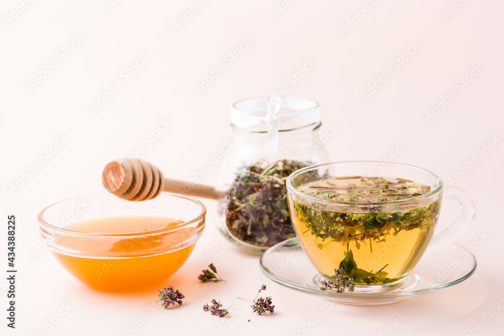 Fresh hot tea with oregano in a cup, honey in a bowl and dry herb in a jar. Herbal medicine and alternative therapy Fresh hot tea with oregano in a cup, honey in a bowl and dry herb in a jar. Herbal medicine and alternative therapy