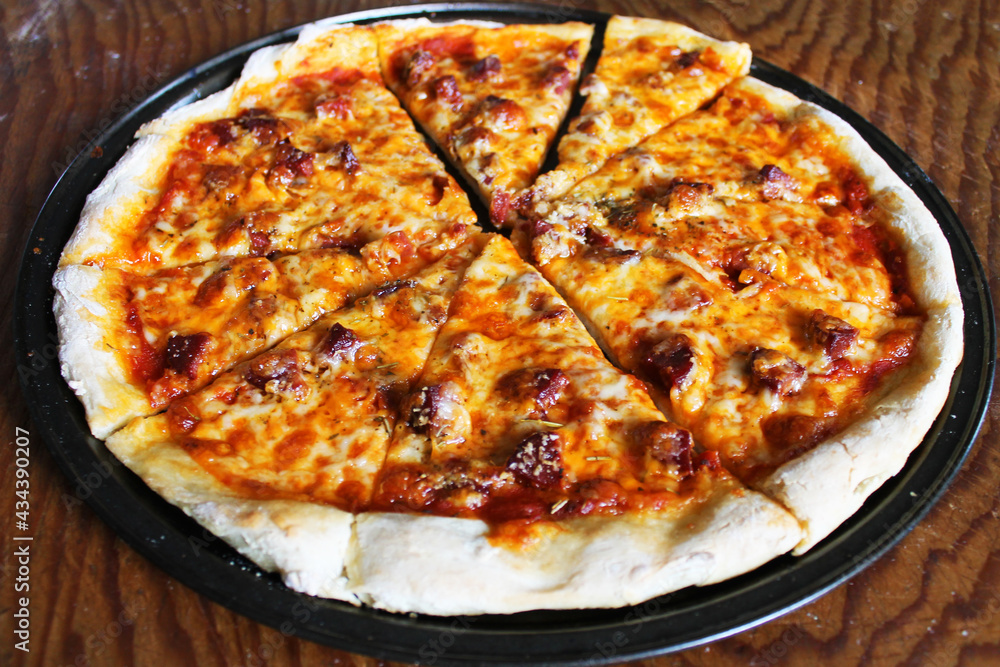 Close-up of fresh baked, homemade pizza, still on pan, on wooden cutting board. Close-up of fresh baked, homemade pizza, still on pan, on wooden cutting board.
