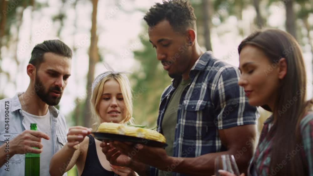 Multiracial group tasting vegetables outside. Friends eating french beans Multiracial group tasting vegetables outside. Friends eating french beans