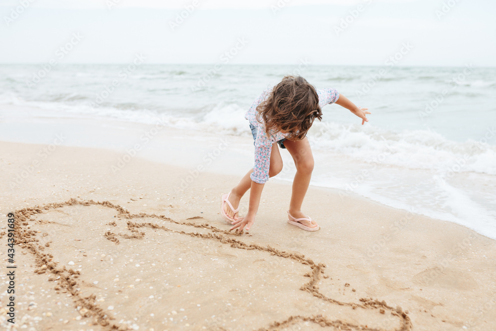 Five years cute curlyFive years cute curly caucasian girl painting on sand on the beach. Five years cute curlyFive years cute curly caucasian girl painting on sand on the beach.