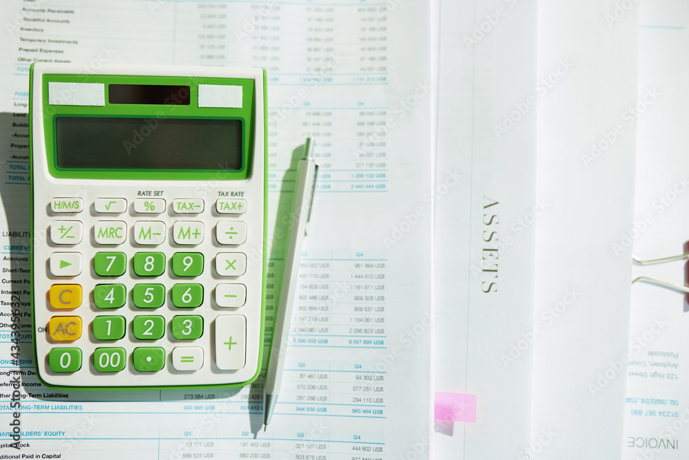 Closeup on desk with documents for taxes, calculator and pen Closeup on desk with documents for taxes, calculator and pen
