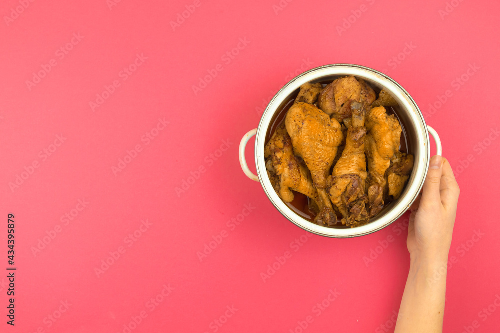 Woman presenting roasted chicken food for a family dinner, minimalist kitchen workspace and flat lay pink background, saucepan in hand, top view and copy space photo Woman presenting roasted chicken food for a family dinner, minimalist kitchen workspace and flat lay pink background, saucepan in hand, top view and copy space photo