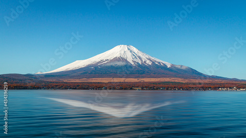 Landscape of Mount Fuji with white snow on top peak of the mountain in clear blue sky sunny day and shadow of the mountain reflect on the lake water. Lake Kawakuchi, Yamanashi, Japan.