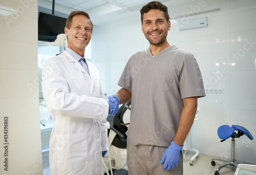 Two male colleagues shaking hands at dental clinic