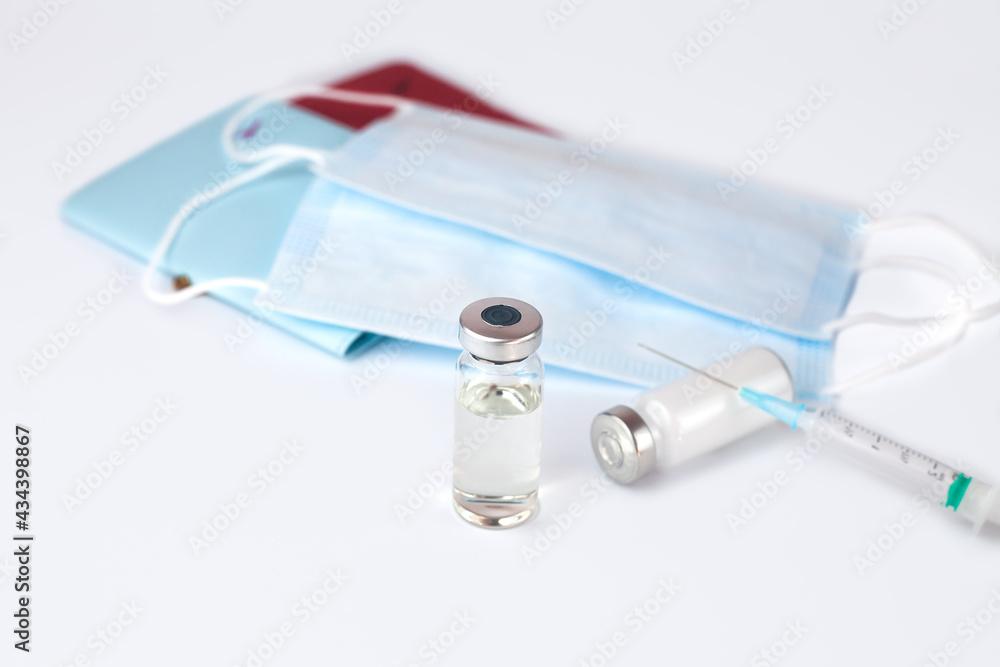 Vaccine, syringe, passports and medical masks on a white background. Safe travel concept. Close-up. Vaccine, syringe, passports and medical masks on a white background. Safe travel concept. Close-up.