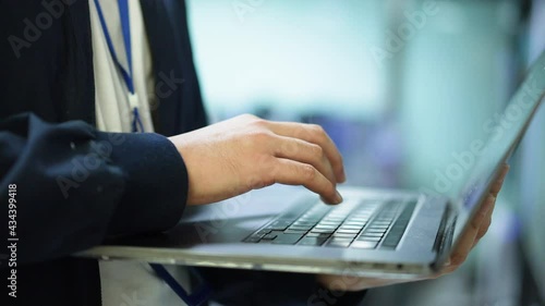 slow motion scene on network engineering man hand typing keyboard laptop to configure command software and check connectivity on ethernet broadband at data center operation room for technology concept