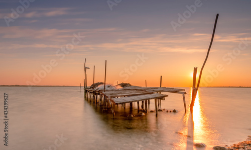 Tableau sur toile Vue d'un ponton de pêche avec un coucher de soleil sur un étang de la Camargue,
