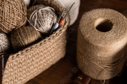 jute crochet material kit: threads, crochet hooks and leather tags in a basket on table