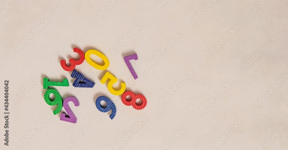 Top view of multicolored small bright children's numbers for development from zero to nine lie randomly on a white background Top view of multicolored small bright children's numbers for development from zero to nine lie randomly on a white background