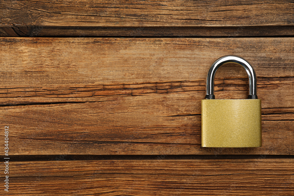 Fototapeta premium Modern padlock on wooden table, top view. Space for text