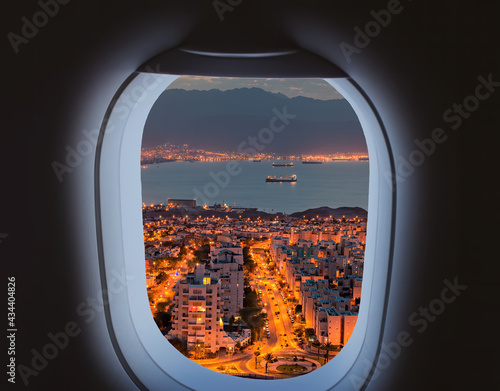 Aerial view of window from landing airplane, night Eilat and Aqaba cities sur...