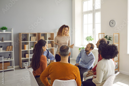 Group therapy. Different people sit in a circle at a support group meeting and listen to a woman who shares her problem. During communication, people listen to each other's stories.