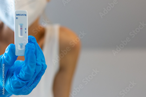 Female Health care worker with blue surgical gloves holding a negative COVID-19 Antigen rapid test 
