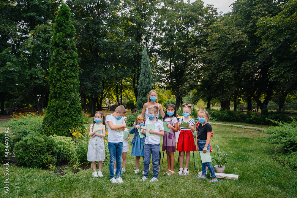 Obraz premium A class of masked school children is engaged in outdoor training during the epidemic. Back to school, learning during the pandemic