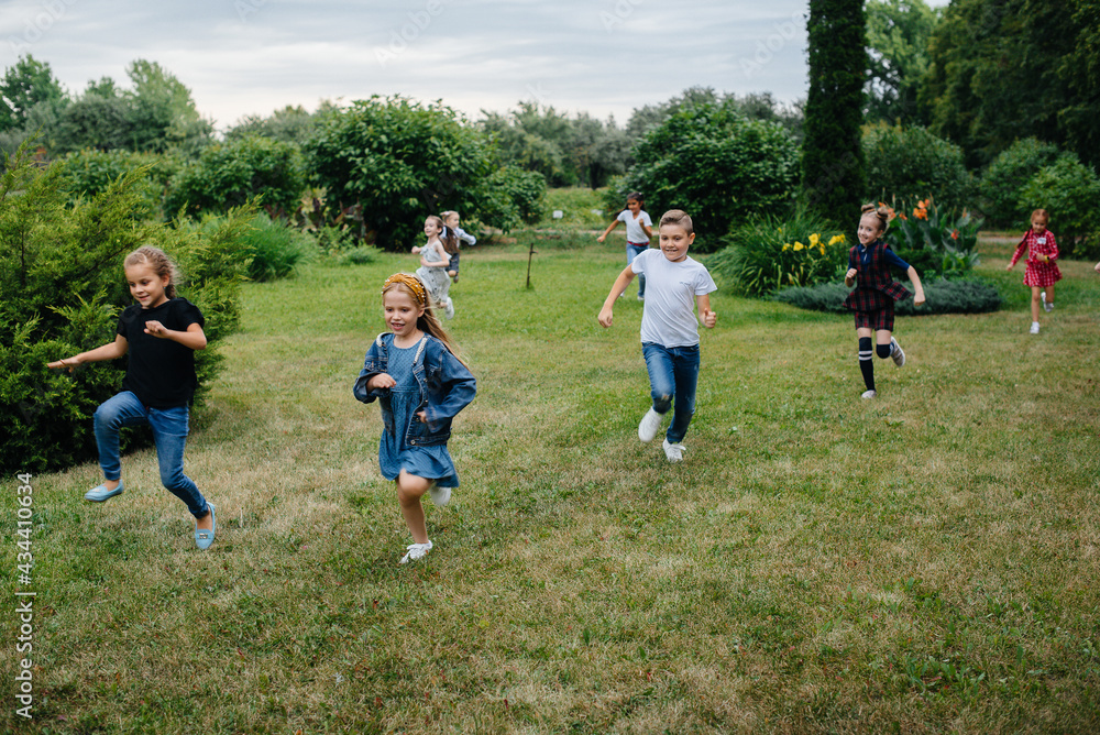 A group of school children runs in the Park in the summer. Happiness, lifestyle. Happy childhood A group of school children runs in the Park in the summer. Happiness, lifestyle. Happy childhood