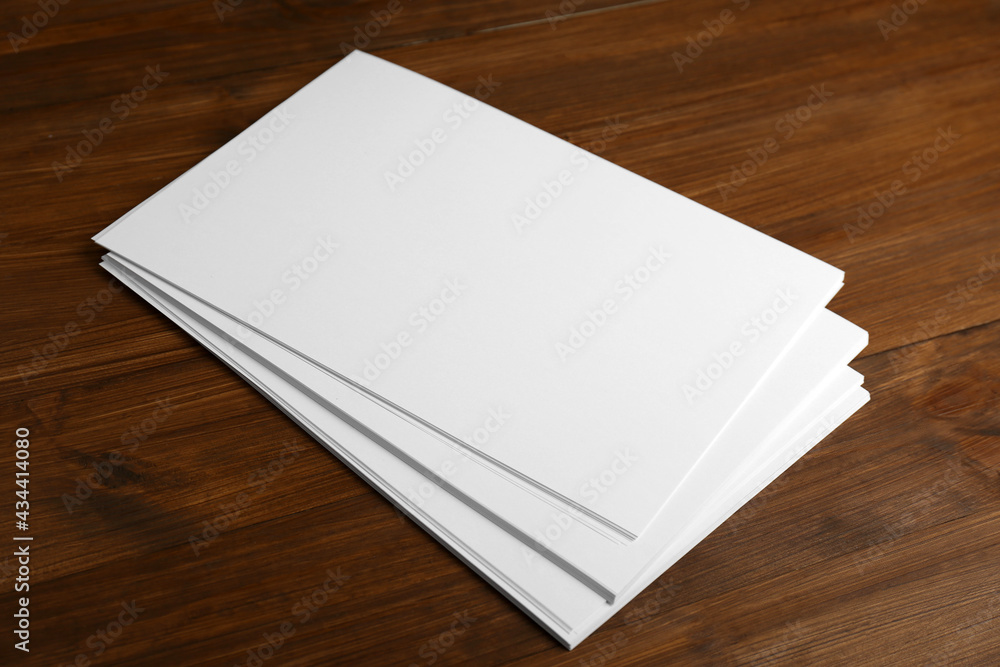 Stack of blank paper sheets on wooden table. Brochure design Stack of blank paper sheets on wooden table. Brochure design