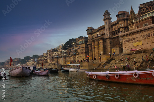 Obraz na płótnie Varanasi, India: People and tourists on wooden boat sightseeing in Ganges river near Munshi ghat against ancient city architecture as viewed from a boat during morning time w salonie