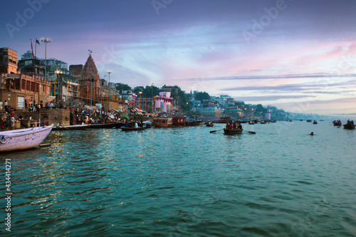 Varanasi  India  People and tourists on wooden boat sightseeing in Ganges river near Munshi ghat against ancient city architecture as viewed from a boat during morning time