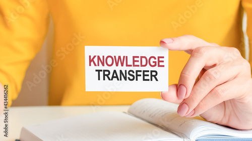 text knowledge transfer written on a white paper card in woman hand, concept