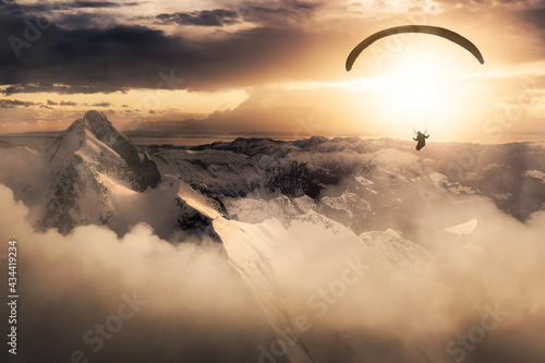 Adventure Composite Image of Paraglider Flying up high in the Rocky Mountains. Sunny Sunset Sky. Aerial Background from British Columbia, Canada. Extreme Sport Concept