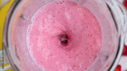 Strawberry and banana milkshake blended in blender with splashes. top view. slow motion. Healthy drink concept photo