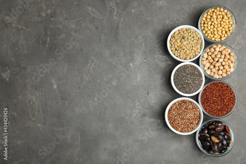 Different grains, seeds and space for text on grey table, flat lay. Veggie diet