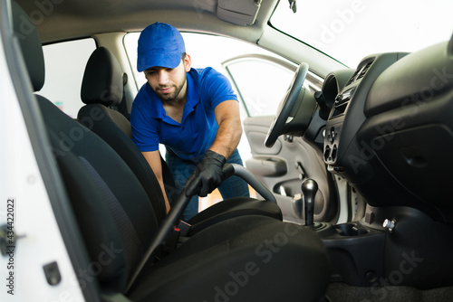 Young man vacuuming the inside of a car