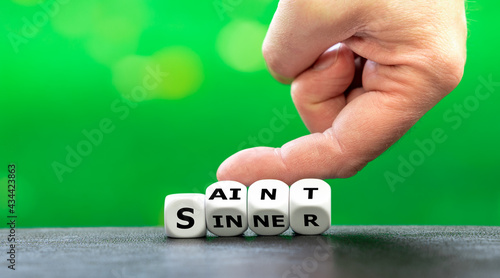 Fotografiet Hand turns dice and changes the word sinner to saint.