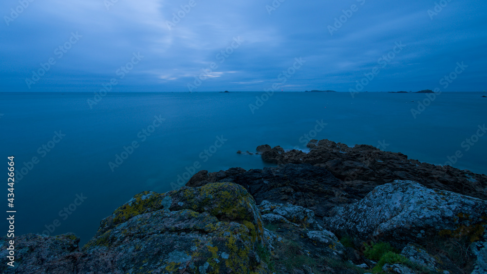 Rochers en mer en pose longue de nuit sous un ciel gris
