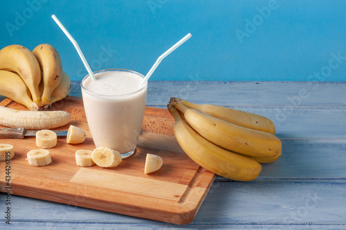 Vista de un batido de plátano en una tabla de cortar 
 con plátanos y rodajas de plátanos alrrededor del batido. photo