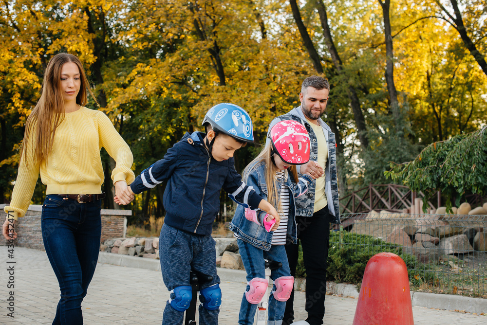 A large happy family rides Segways and electric scooters in the Park on a warm autumn day during sunset. Family vacation in the Park. A large happy family rides Segways and electric scooters in the Park on a warm autumn day during sunset. Family vacation in the Park.