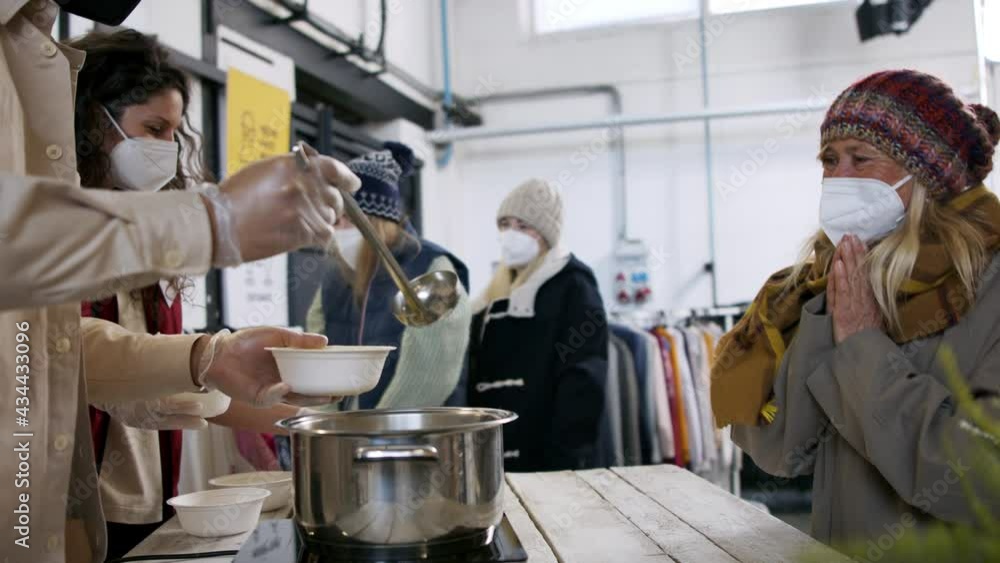 Volunteers serving hot soup for homeless in community charity donation center, coronavirus concept. Volunteers serving hot soup for homeless in community charity donation center, coronavirus concept.