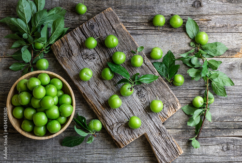 Fresh ripe organic green plums or greengage in bowl on rustic background, heap of summer fruits concept photo