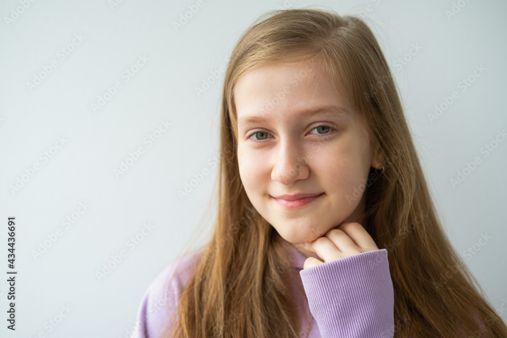 portrait of beautiful teenage girl with long hair in purple hoodie standing against white wall portrait of beautiful teenage girl with long hair in purple hoodie standing against white wall