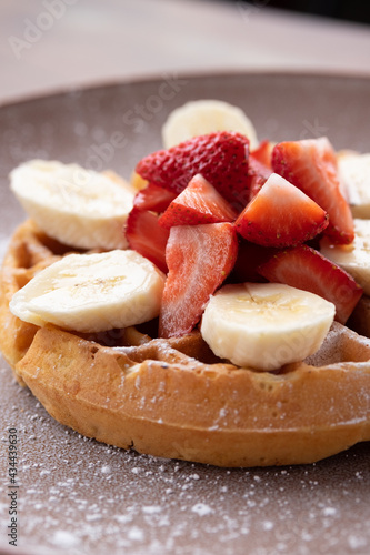 Waffle with strawberry, banana, and confectioner's sugar.