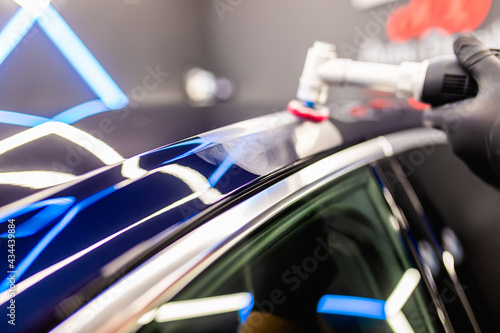 Car detailing - Man with orbital polisher in repair shop polishing car. Selective focus..