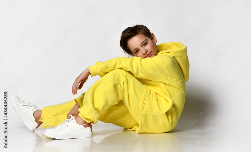 Stylish active guy in a bright yellow tracksuit having fun on a white background. The concept of comfortable clothing, children's sports style and active lifestyle. Stylish active guy in a bright yellow tracksuit having fun on a white background. The concept of comfortable clothing, children's sports style and active lifestyle.