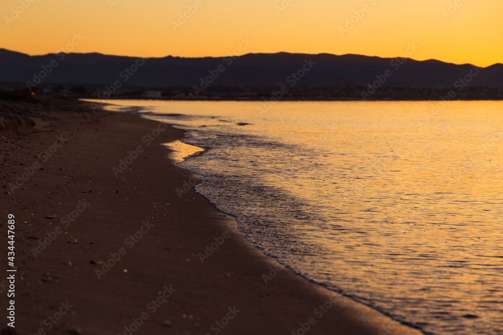 Small waves view crushing the shore of Poetto beach at sunrise